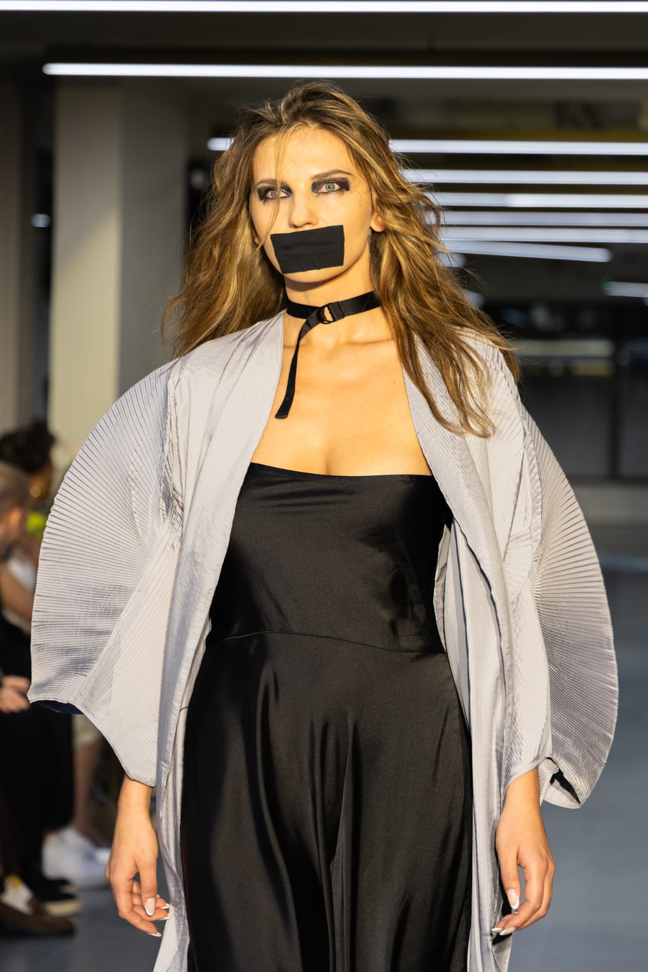 Model in a grey pleated kimono over a black slip dress
