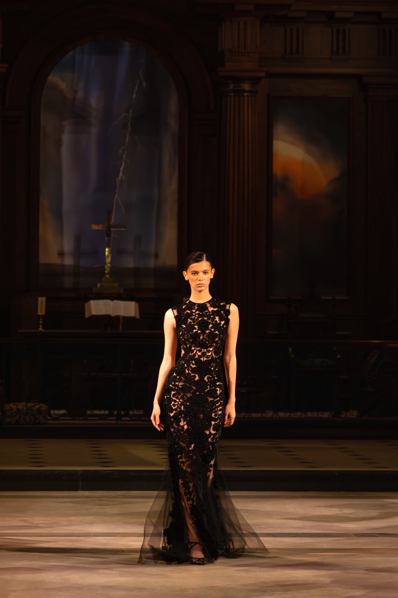 Model in a black lace gown walking a cathedral runway