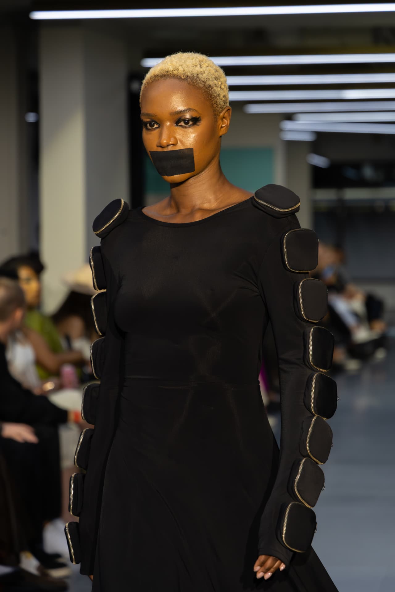 Model in a black structured dress with zipped shoulder pads