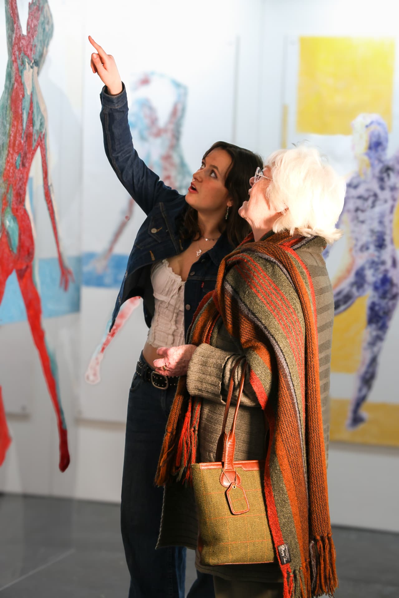 Visitor pointing out a detail in a painting to another guest