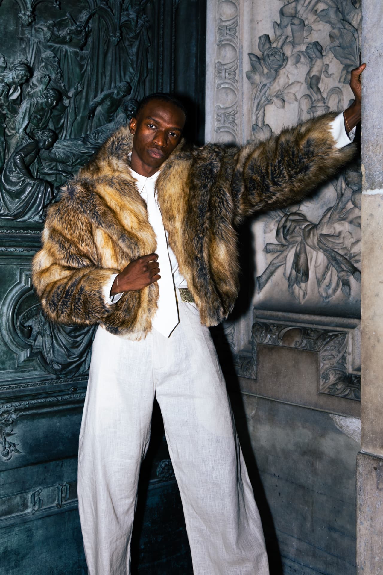 Model in a tan faux-fur coat and white linen suit
