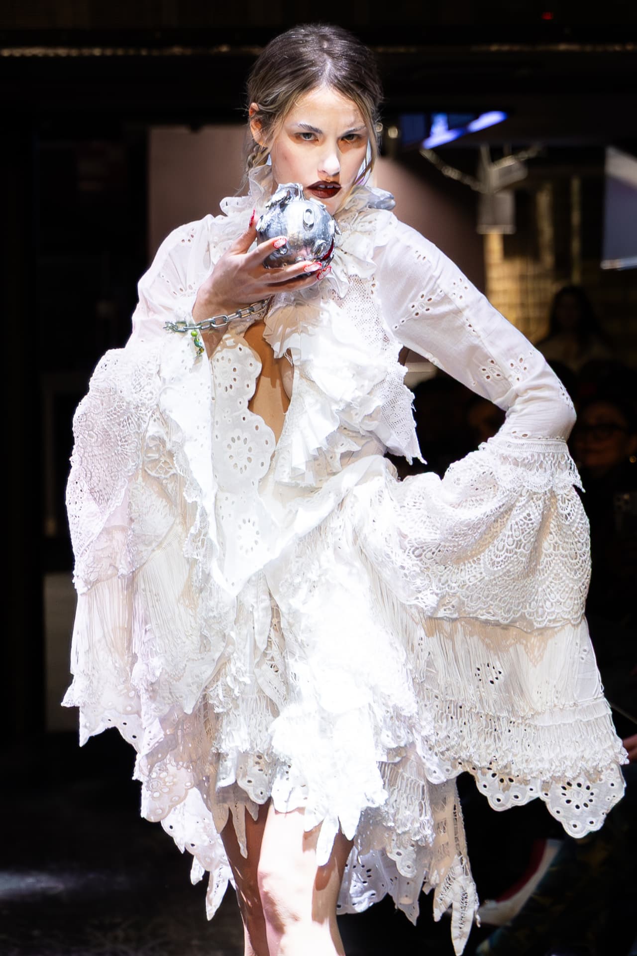 Model in tiered white broderie anglaise holding a silver orb