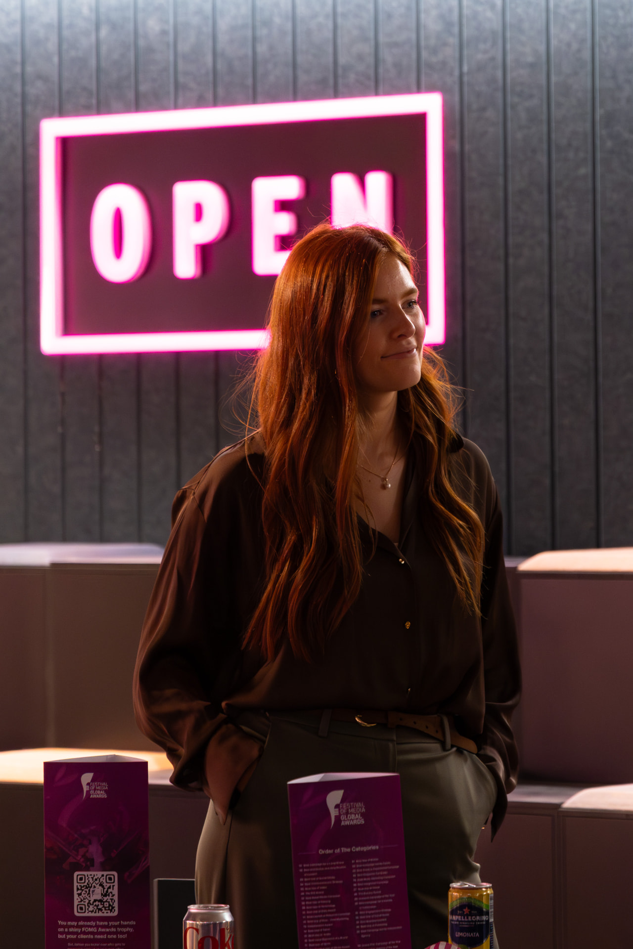Guest beside the neon OPEN sign and awards trophies