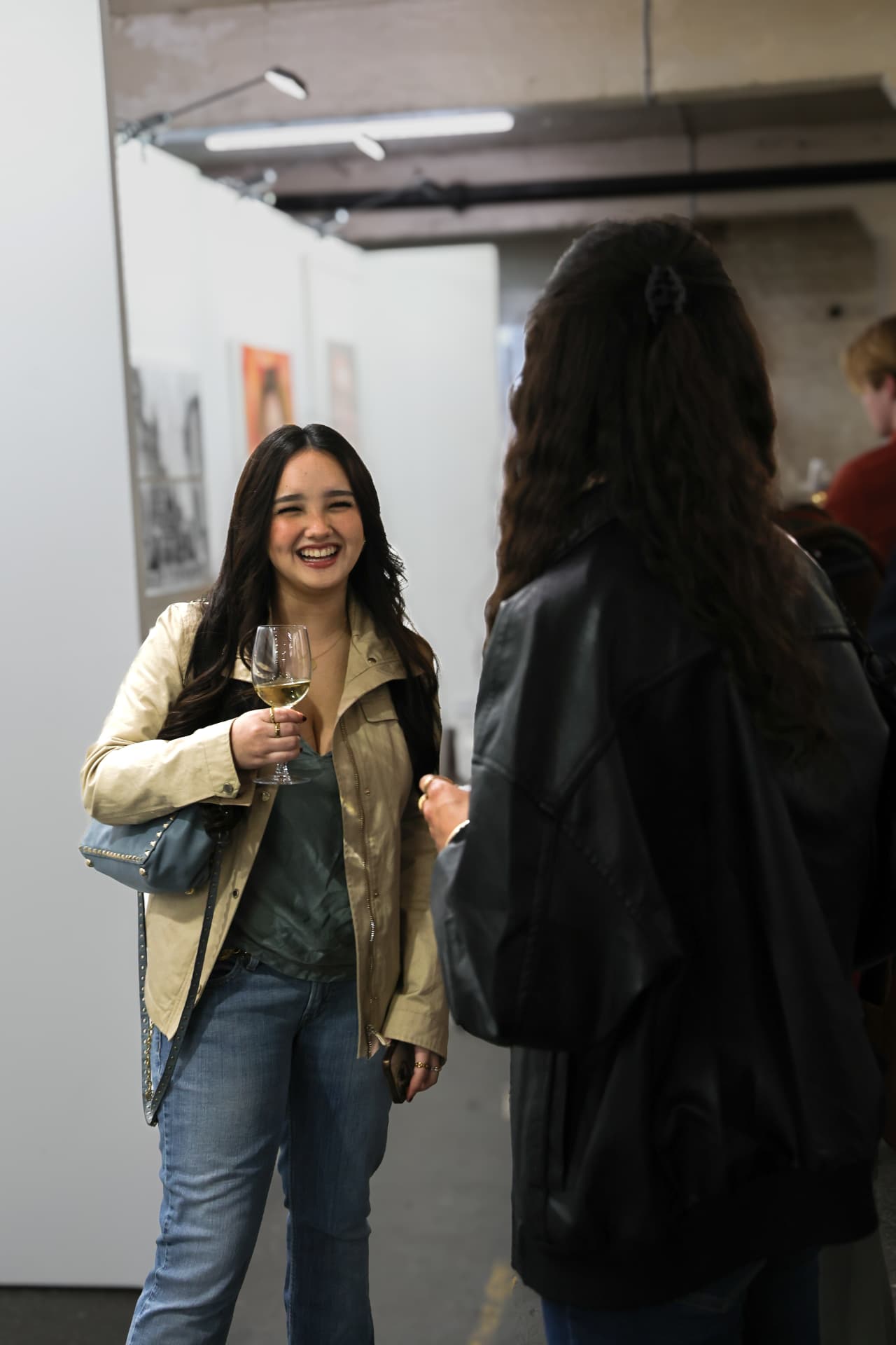 Guest laughing with a glass of wine at the private view