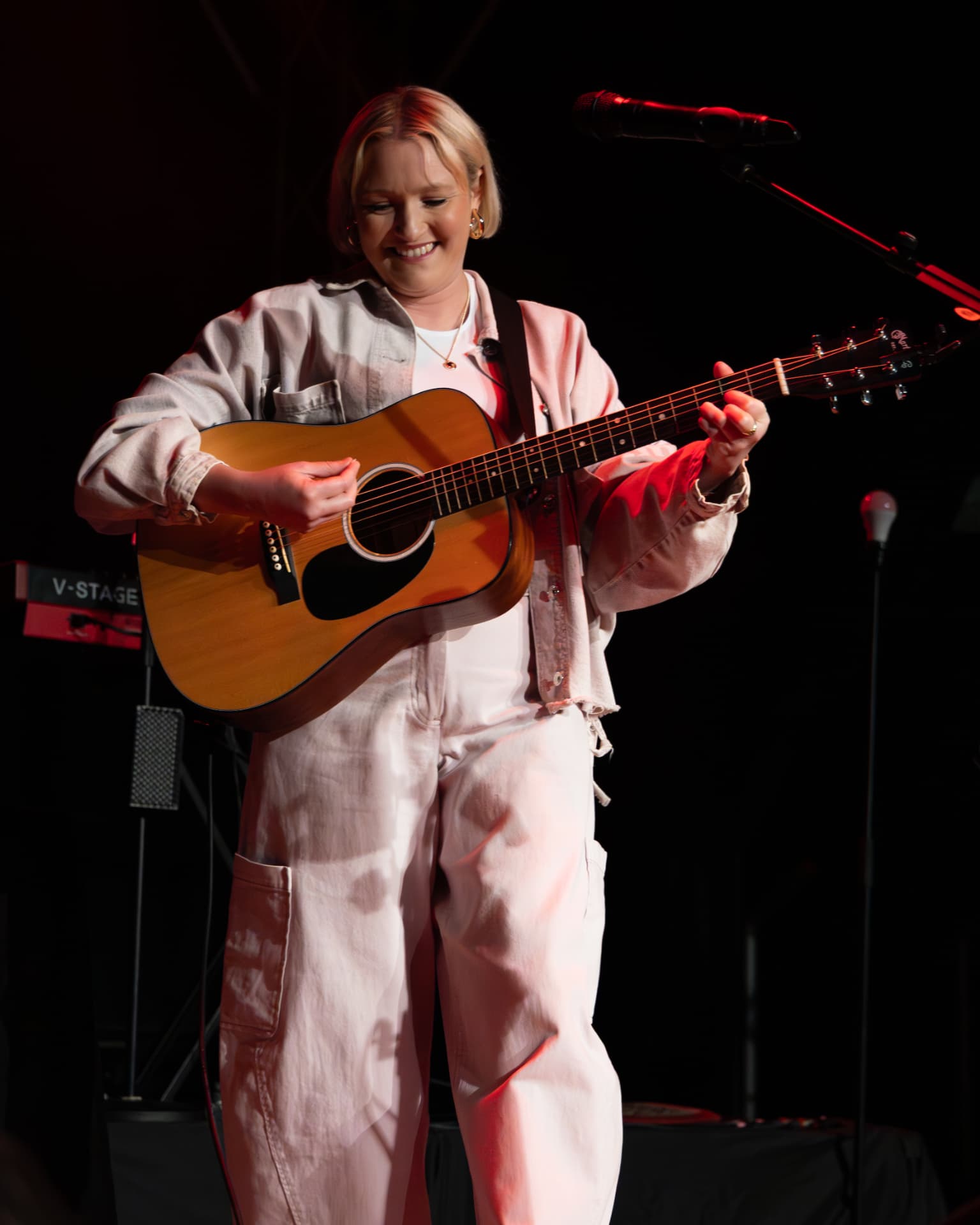 Molly Warburton looking down at her guitar on stage