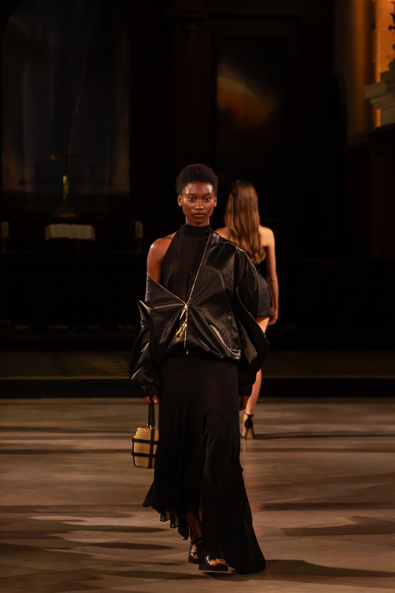 Model in a black satin bomber and flowing maxi skirt