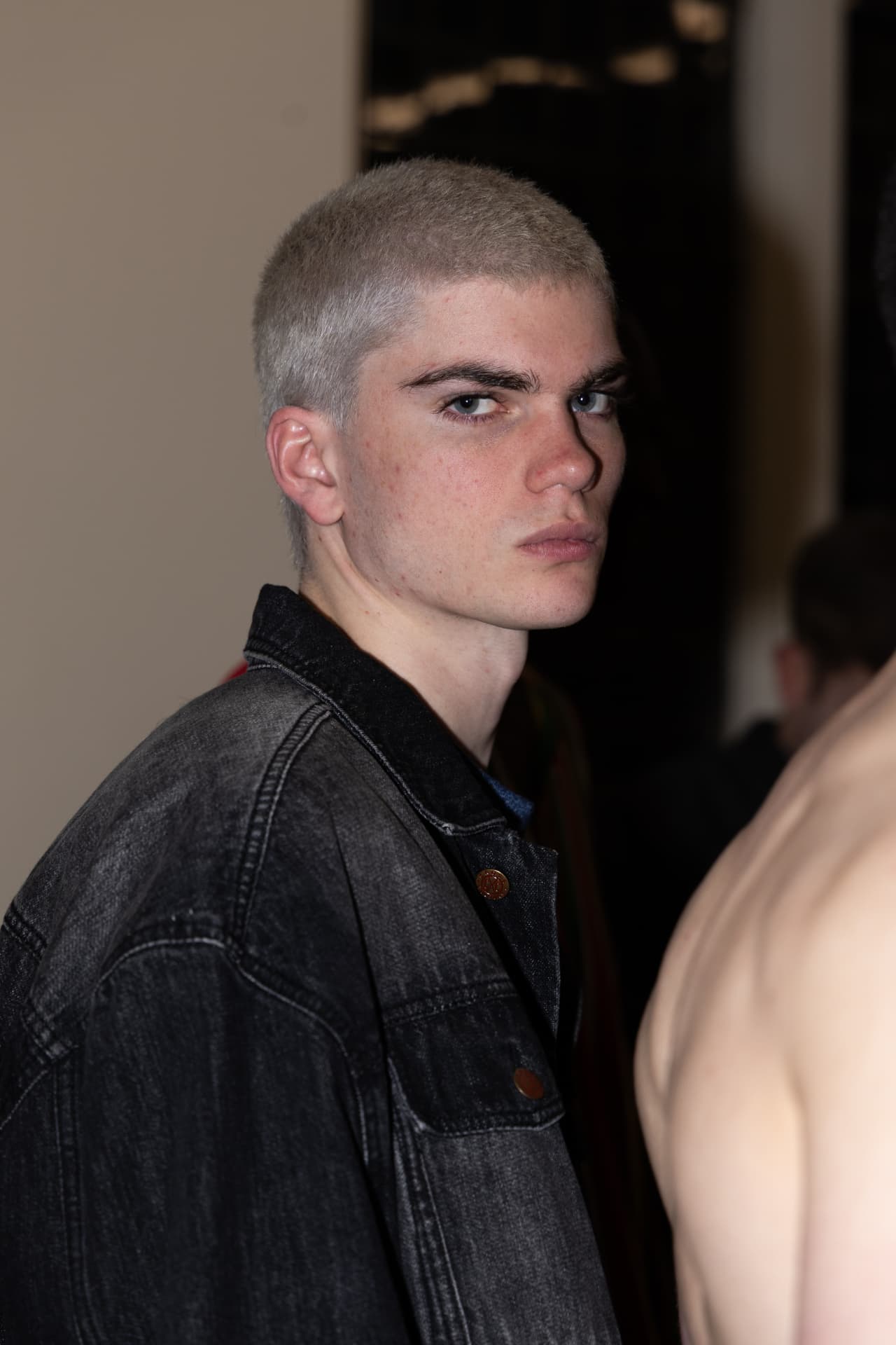 Model in washed black denim jacket backstage