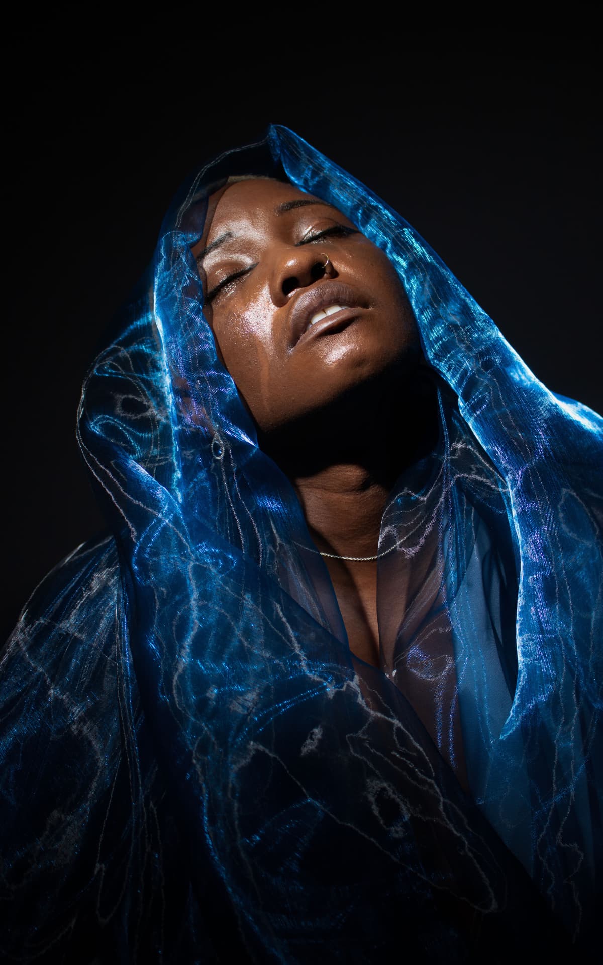 Model draped in blue organza with head tilted back