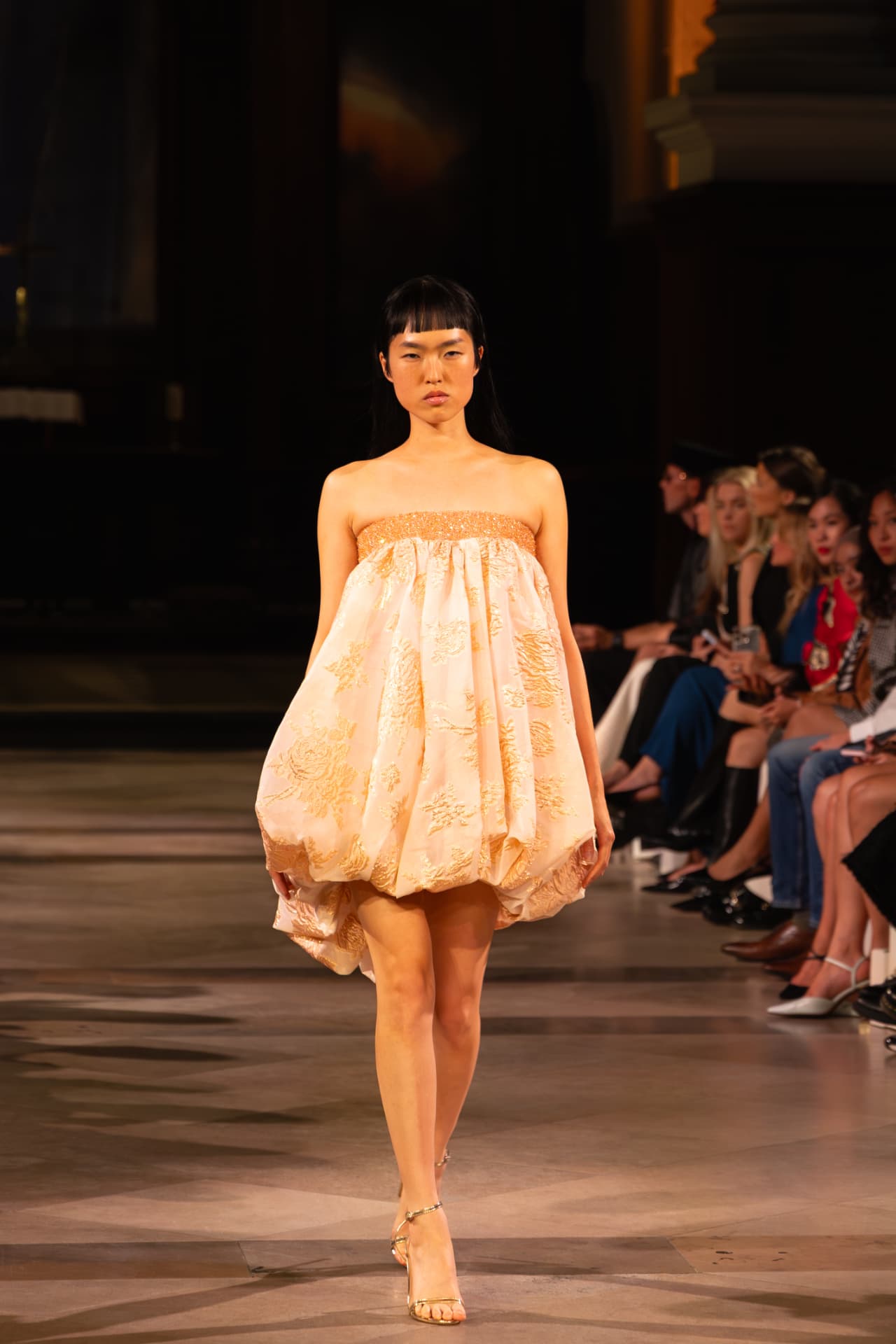 Model in a peach embroidered bubble mini dress