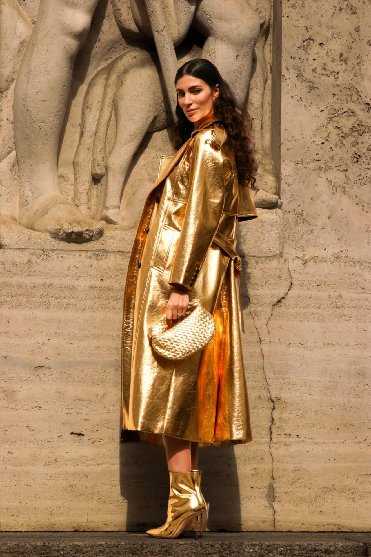 Guest in a full-length gold metallic trench coat and boots