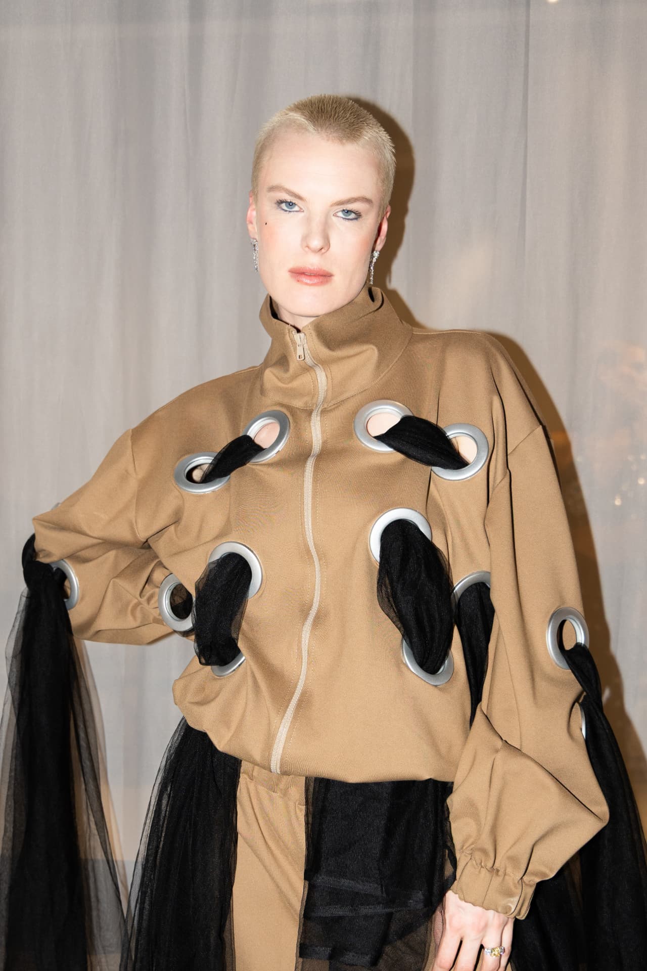 Model in tan eyelet jacket with black tulle