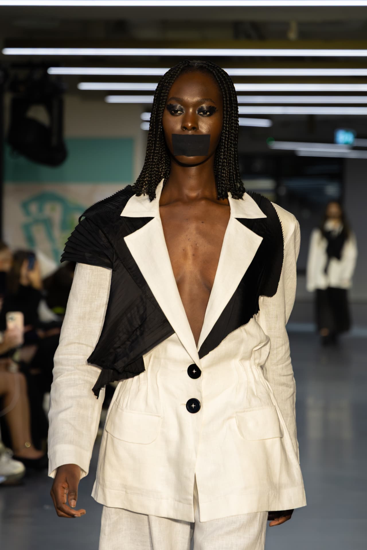 Model in a cream linen suit with black pleated panel
