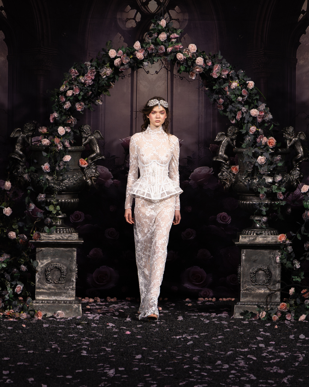 Model in an ivory lace corset gown beneath a rose arch