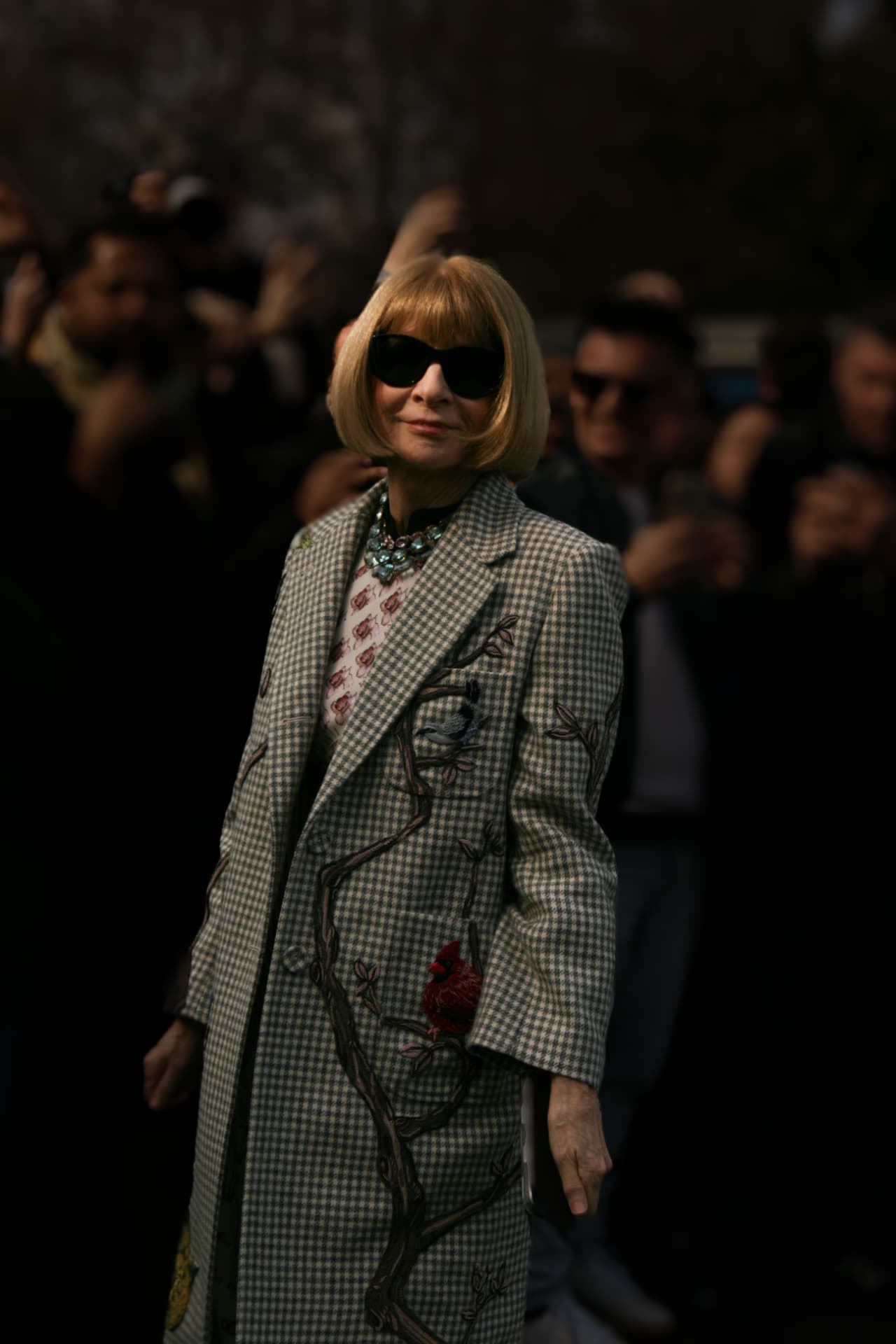 Editor in an embroidered checked coat outside a show